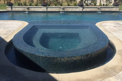 Modelo de piscina con fuente infinita contemporánea grande a medida en patio trasero con adoquines de piedra natural
