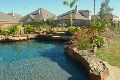 Cette image montre une grande piscine naturelle et latérale chalet sur mesure avec un bain bouillonnant et des pavés en pierre naturelle.