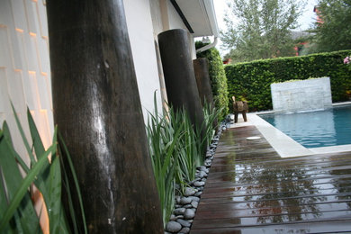 Large transitional backyard rectangular infinity pool fountain photo in Miami with decking