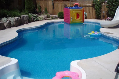 Ejemplo de piscina grande en patio trasero con losas de hormigón
