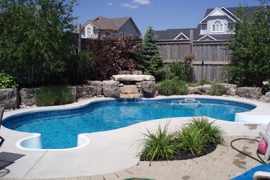 Foto de piscina con fuente moderna grande a medida en patio trasero con losas de hormigón