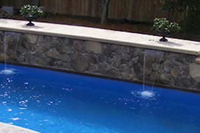 Imagen de piscina con fuente rectangular en patio trasero con adoquines de hormigón