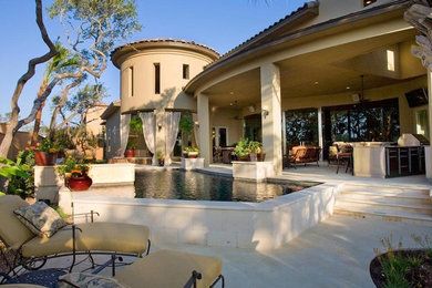 Large tuscan backyard concrete paver and custom-shaped aboveground hot tub photo in Austin