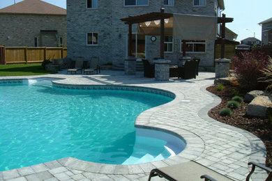 Large backyard concrete paver and custom-shaped natural pool photo in Toronto