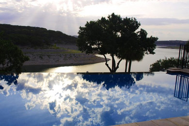 Modelo de piscina infinita clásica renovada de tamaño medio rectangular en patio trasero con adoquines de piedra natural