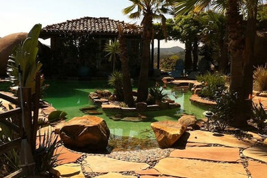 Esempio di una piscina personalizzata dietro casa con fontane e pavimentazioni in pietra naturale