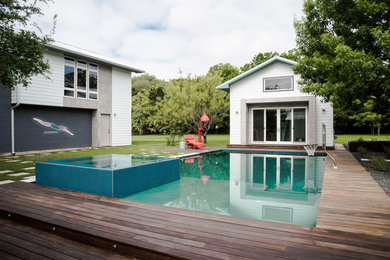 Exemple d'un grand couloir de nage arrière éclectique rectangle avec un bain bouillonnant et une terrasse en bois.