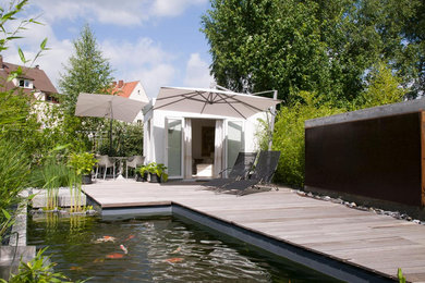 Réalisation d'un Abris de piscine et pool houses arrière design de taille moyenne et sur mesure avec une terrasse en bois.
