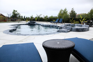 Foto de piscina tropical grande a medida en patio trasero con losas de hormigón