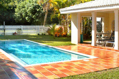 Ejemplo de piscina alargada contemporánea rectangular en patio trasero con suelo de baldosas