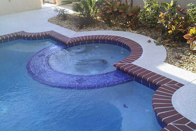 Diseño de piscinas y jacuzzis de estilo americano a medida en patio trasero con adoquines de ladrillo