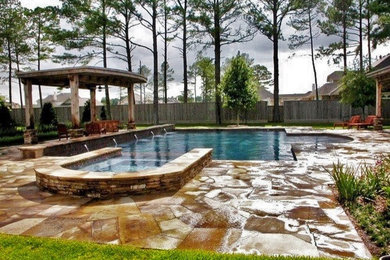 Großer Moderner Pool hinter dem Haus in rechteckiger Form mit Wasserspiel und Stempelbeton in Houston