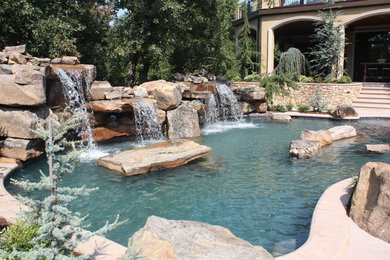 Diseño de piscina con fuente clásica de tamaño medio a medida en patio trasero con adoquines de piedra natural