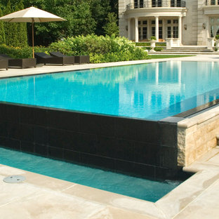 Foto di una piscina a sfioro infinito minimal rettangolare dietro casa con fontane