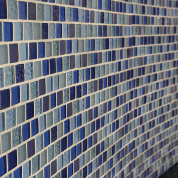 Glass tile projects- 1” X 1” mosaic blue glass tile accent the raised bond beam,