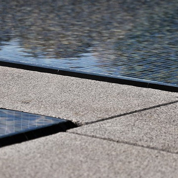 glass tile swimming pool + spa with perimeter overflow + granite decking
