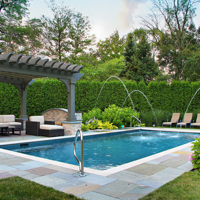 Example of a classic backyard stone and rectangular pool fountain design in Chicago