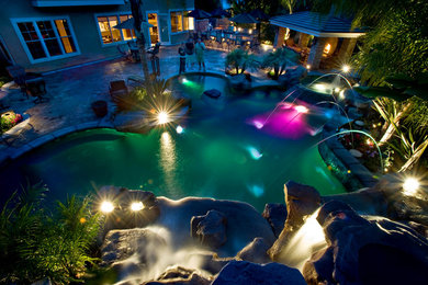 Pool fountain - large tropical backyard stamped concrete and custom-shaped pool fountain idea in Los Angeles