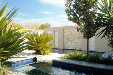 Foto de piscina con fuente contemporánea pequeña a medida en patio trasero con adoquines de piedra natural