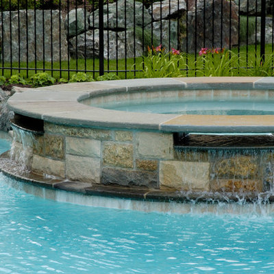 Example of a large mountain style backyard stone natural hot tub design in Chicago