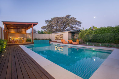 Cette photo montre une grande piscine arrière moderne ronde avec un bain bouillonnant et une terrasse en bois.