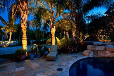 Esempio di una piscina tropicale personalizzata di medie dimensioni e dietro casa con pavimentazioni in pietra naturale