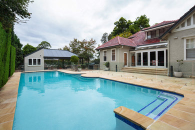 Imagen de piscina alargada clásica extra grande rectangular en patio trasero con adoquines de piedra natural