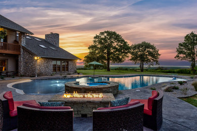Huge arts and crafts backyard stamped concrete and custom-shaped hot tub photo in Dallas