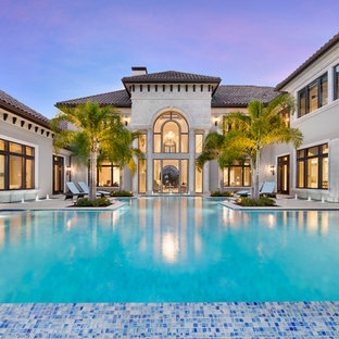 Expansive traditional backyard custom-shaped infinity pool in Miami with a water feature and natural stone pavers.