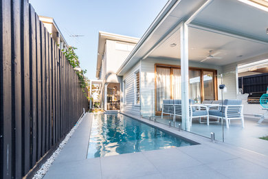 Modelo de piscina alargada escandinava de tamaño medio rectangular en patio lateral con adoquines de hormigón