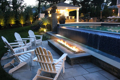 На фото: большой прямоугольный бассейн-инфинити на заднем дворе в современном стиле с домиком у бассейна и мощением тротуарной плиткой с