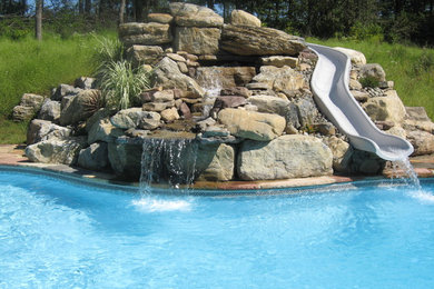 Inspiration for a large timeless backyard stone and custom-shaped water slide remodel in New York