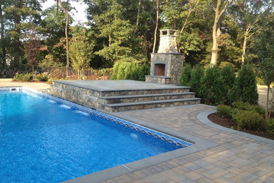 Modelo de piscina con fuente alargada tradicional renovada grande rectangular en patio trasero con suelo de hormigón estampado
