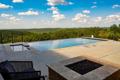 Example of a huge minimalist backyard concrete and rectangular infinity and privacy pool design in Austin