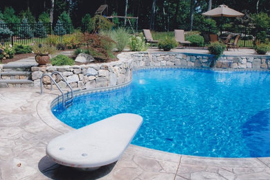 Imagen de piscina con fuente grande a medida en patio trasero con adoquines de piedra natural