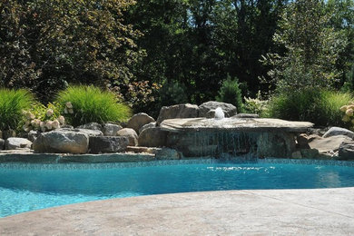 Diseño de piscina con fuente grande a medida en patio trasero con adoquines de piedra natural
