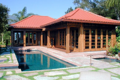 Modelo de piscinas y jacuzzis alargados asiáticos de tamaño medio rectangulares en patio trasero con adoquines de piedra natural
