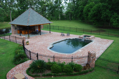 Ejemplo de casa de la piscina y piscina exótica rectangular en patio trasero con adoquines de ladrillo