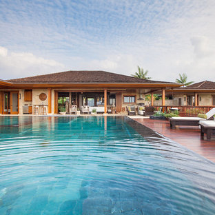 Ispirazione per una grande piscina a sfioro infinito tropicale rettangolare dietro casa con pedane
