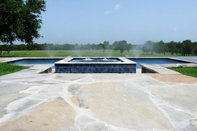 Imagen de piscinas y jacuzzis contemporáneos grandes rectangulares en patio trasero con adoquines de piedra natural