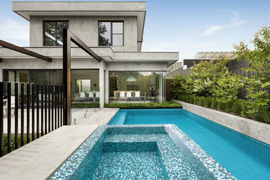 Diseño de piscina infinita actual grande rectangular en patio trasero con losas de hormigón