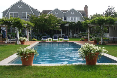 Diseño de casa de la piscina y piscina alargada tradicional grande rectangular en patio trasero con adoquines de ladrillo