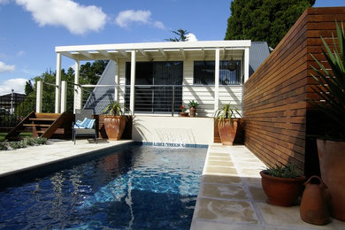 Diseño de piscina con fuente natural actual pequeña rectangular en patio trasero con adoquines de hormigón