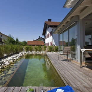 Rustikaler Schwimmteich hinter dem Haus in rechteckiger Form mit Dielen in München