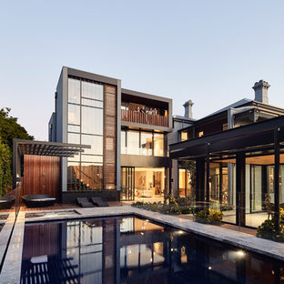 Large contemporary backyard rectangular aboveground pool in Melbourne with a pool house and natural stone pavers.