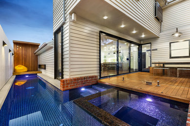 Foto de piscina alargada contemporánea en forma de L en patio lateral con entablado