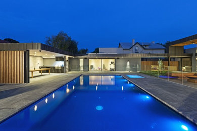 Bild på en stor funkis rektangulär pool på baksidan av huset, med marksten i betong