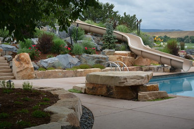 Photo of a large contemporary back rectangular lengths swimming pool in Denver with a water slide and concrete slabs.