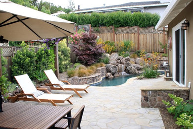 Ejemplo de piscina contemporánea de tamaño medio a medida en patio trasero con adoquines de hormigón
