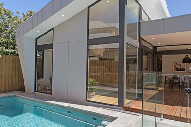 Стильный дизайн: естественный, прямоугольный бассейн среднего размера на заднем дворе в стиле модернизм с покрытием из плитки и забором - последний тренд
